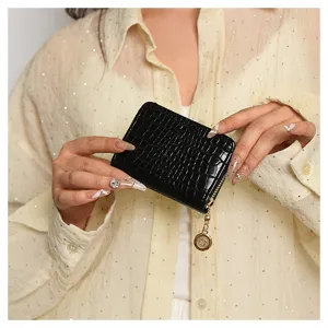 Close-up detail of the black crocodile textured patent leather card holder with zipper.