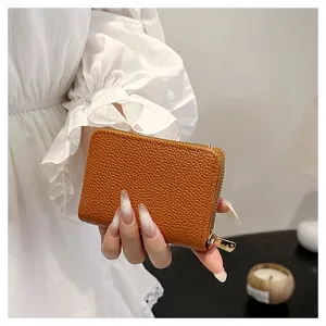 Detalle de tarjetero de piel graneada marrón, cartera compacta con cremallera en primer plano.