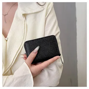 Primer plano detallado de una cartera tarjetero de cuero texturizado negro con cremallera.