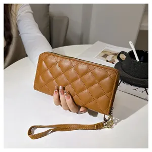 Detail view of brown quilted long wallet, elegant diamond pattern clutch with secure zip closure.