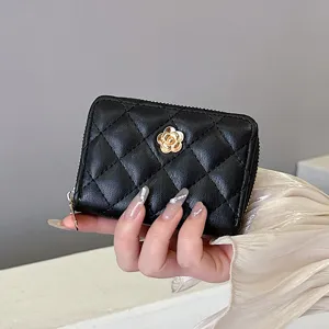 Portafoglio porta carte nero trapuntato con elegante emblema di fiore di camelia dorata e zip sicura.