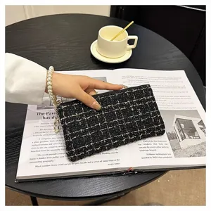 Elegant black tweed clutch bag detail showing delicate woven fabric and gold zipper pull.
