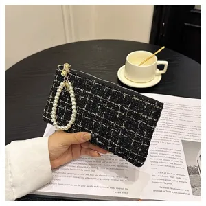 Close-up detail of black tweed woven coin purse clutch with elegant pearl strap design.
