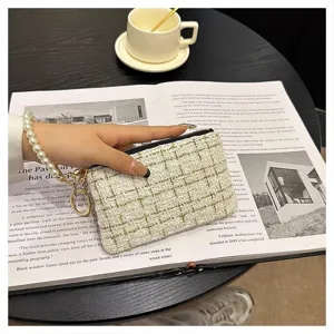 Detail view of the elegant tweed coin purse with pearl strap, showing delicate woven texture.