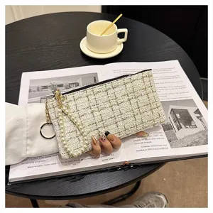 Detail view of woven tweed mini clutch wallet with elegant pearl strap and metal ring.