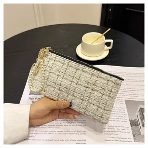 Close-up detail of women tweed clutch bag with pearl strap and zipper closure, elegant style.