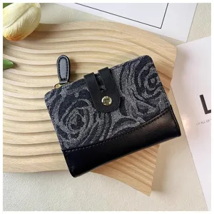 Close-up detail of the black denim rose patterned mini wallet with snap button and zipper.
