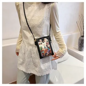 Crossbody phone bag detail view, black vertical leather pouch with cute art illustration.