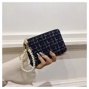 Detail view of the elegant tweed coin purse featuring pearl wrist strap and gold zipper.