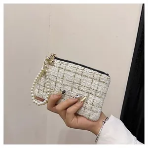 Detail view of woven tweed coin purse with pearl wrist strap and secure zip closure for cards.