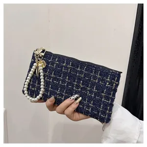 Detail view of navy tweed zipped coin purse with pearl wrist strap, elegant woven card holder.