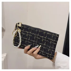 Close-up detail of the black tweed coin purse with elegant faux pearl wrist strap and zipper.