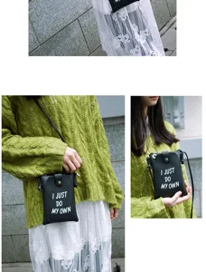 Detail view of a stylish black mini phone cross-body bag with chic white graphic print.