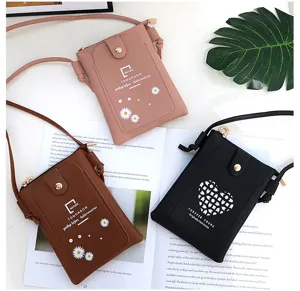 Detailed view of mini crossbody phone bags in pink, brown and black with cute daisy and heart prints.