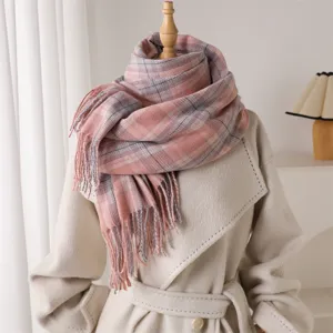 Detailed view of a soft pink plaid winter scarf with elegant tassels displayed warmly.