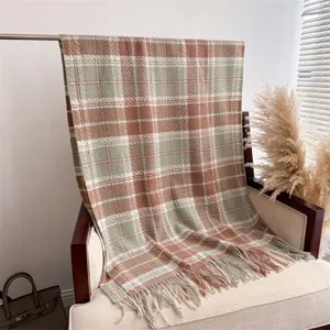 Detailed close-up view of a cozy plaid boucle shawl with tassels displayed on a warm chair.
