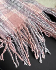 Close-up view of soft pink grey plaid scarf detail featuring delicate fringe tassel edges.