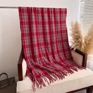 Cozy red plaid cashmere-feel scarf detail, featuring soft fringe edges and warm texture.