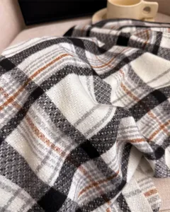 Close-up of cozy black and white plaid cashmere-feel winter scarf texture detail.