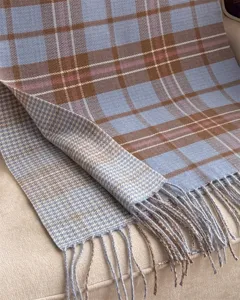 Detailed view of a soft plaid imitation cashmere shawl scarf with fringe and reversible pattern.