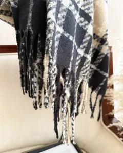 Close-up view of the cozy black and white plaid boucle scarf texture and fringe detail.