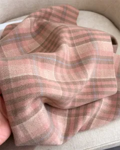 Detailed view of soft pink plaid cashmere-feel winter shawl, cozy scarf texture close up.