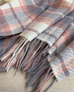 Close-up detail of cozy plaid cashmere-feel winter scarf with elegant fringed hems.