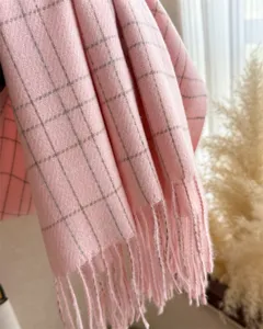 Gros plan détaillé d'une écharpe à carreaux rose douce avec des franges chaleureuses.