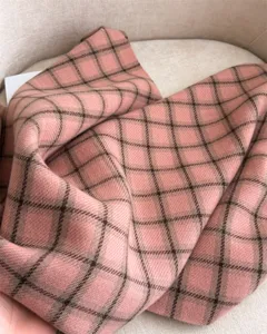 Detailed close-up view of a soft pink and brown plaid winter scarf with cozy textile texture.