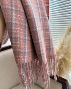 Nahaufnahme eines weichen rosa-lila karierten Fransenschals, kuscheliges Winteraccessoire.