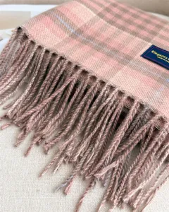 Close-up detail of soft pink plaid cashmere-feel winter scarf with fringe texture.
