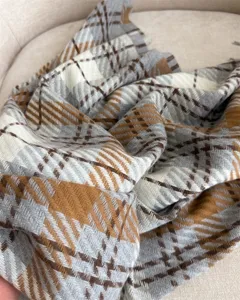 Detailed shot of cozy faux cashmere plaid scarf with stylish tassels for autumn and winter warmth.