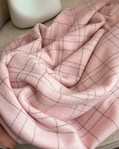 Gros plan sur l'écharpe douce rose à carreaux imitation cachemire, montrant texture et drapé.