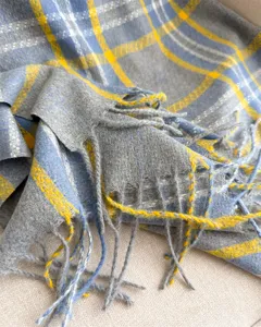 Primo piano della morbida sciarpa a quadri effetto cashmere, con dettagli di frange.