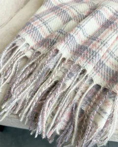 Close-up view of the soft plaid winter scarf highlighting its delicate texture and cozy fringe edges.