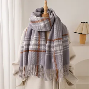 Close-up detail of the cozy grey plaid tassel scarf, showing soft wool-like texture.