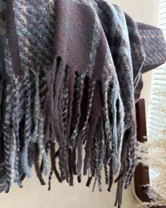 Close-up detail of winter plaid loop yarn tassel scarf texture, soft cashmere imitation shawl.
