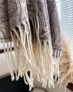 Close-up detail of soft winter paisley pattern fringe scarf, cozy cashmere-feel texture.