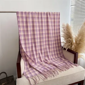 Detail view of a purple and beige plaid cashmere-feel scarf shawl with stylish fringe ends.