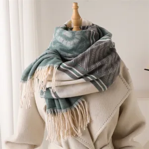 Close-up detail of soft green and grey patterned scarf featuring elegant fringe design.