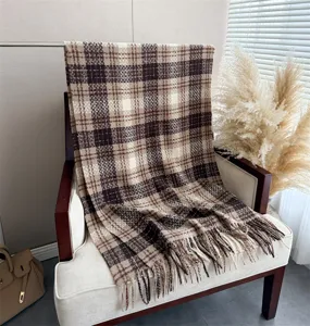 Detailed view of cozy plaid cashmere-feel fringed winter scarf draped neatly on a chic chair.
