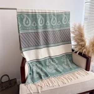 Detailed view of a retro paisley knitted blanket shawl draped on chair, cozy fringe boho decor.