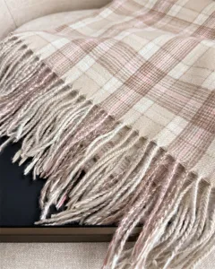 Close-up detail of soft plaid cashmere-feel scarf with delicate fringe trim, winter style.