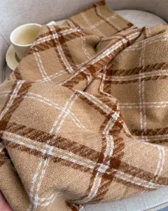 Detailed view of cozy brown plaid boucle cashmere-feel winter scarf, soft warm tassel shawl.