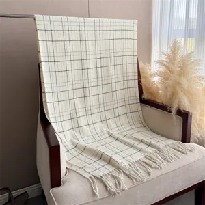 Vue détaillée d'une écharpe à carreaux style cachemire avec franges sur un fauteuil.