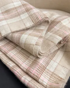 Detailed close-up shot of a cozy beige plaid faux cashmere winter scarf with soft tassel edges.