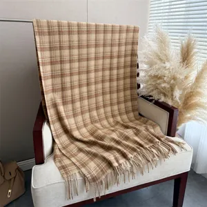 Detail shot of a cozy cashmere-imitation plaid scarf draped on a chic armchair for autumn.