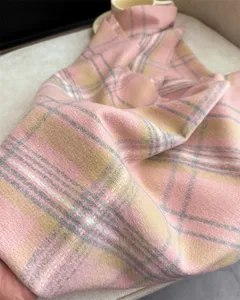 Close-up view of a soft pink plaid cashmere-like scarf detail, cozy winter fashion accessory.