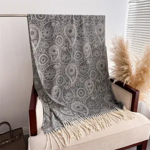 Close-up of the elegant paisley pattern and fringe detail on the cozy gray winter shawl scarf.