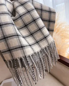 Detailed close-up of a cozy cashmere-feel plaid scarf with classic fringe for autumn winter.